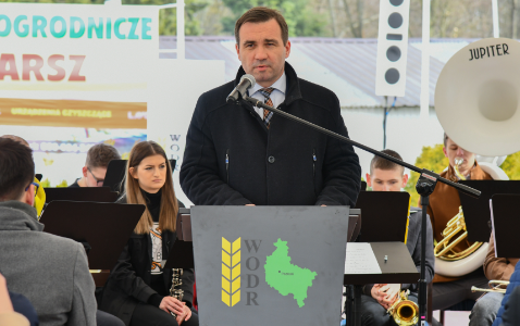 Dyrektor WODR Jacek Sommerfeld stoi w czarnym płaszczu przy mównicy i przemawia.