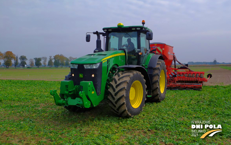 Na zdjęciu zielony ciągnik marki John Deer z siewnikiem rzędowym Kuhn Aurock 6000 RC podczas siewu